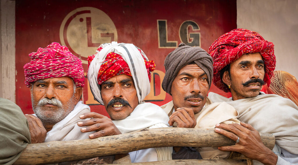 Four Rajasthani tribesmen in India in a queue all looking in the same direction towards their temple