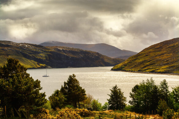 Loch Seaforth with Scottish pine trees, hills, mountains, and a yacht on the loch.