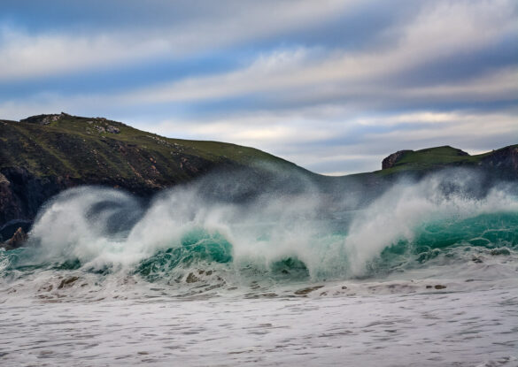 Mangersta beach with a huge aquamarine wave curling over, the spume is blowing backwards due to high winds.