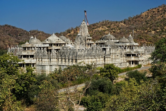 The Ranakpur Jain Temple, with its complex marble architecture and numerous shikhara towers, stands surrounded by lush greenery and the rolling hills of the Aravalli Range.