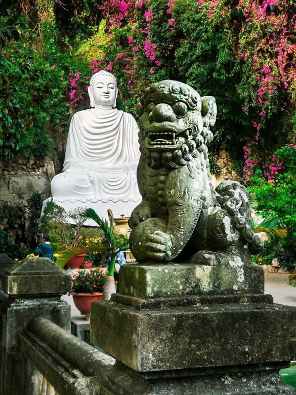 A white Buddha statue and a traditional dragon sculpture at the Marble Mountain entrance, Vietnam