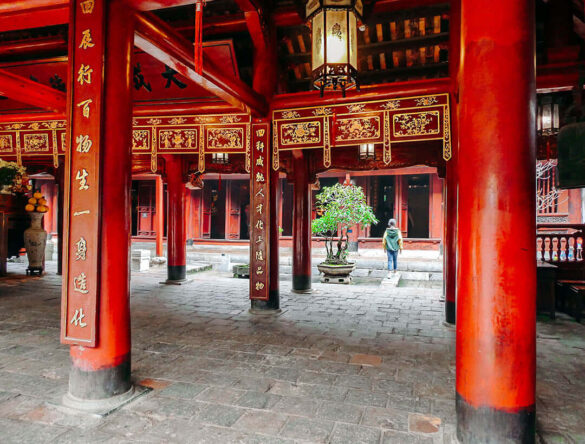 Interior of a Buddhist temple with red columns and golden inscriptions in Hanoi, Vietnam