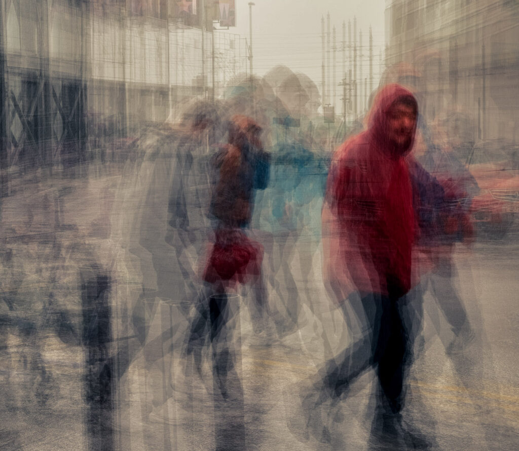 A blurred street scene with indistinct figures moving through a rainy cityscape, their forms blending into a wash of colors."