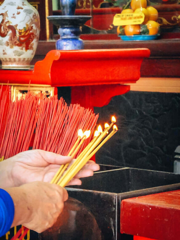 Hands holding incense sticks at a Buddhist Temple in Hanoi, Vietnam