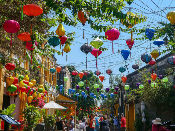 Colorful lanterns strewn across a busy street during the day in Hoi An, Vietnam