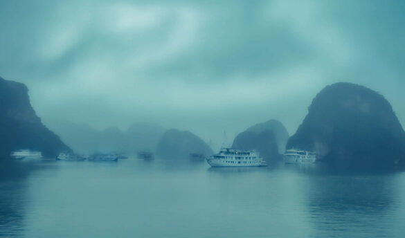 A misty evening view of Halong Bay, Vietnam, with silhouettes of limestone karsts