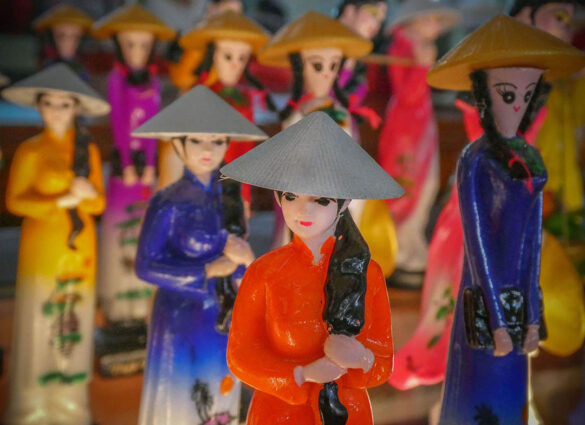 A close-up of colorful Vietnamese figurines wearing traditional hats.