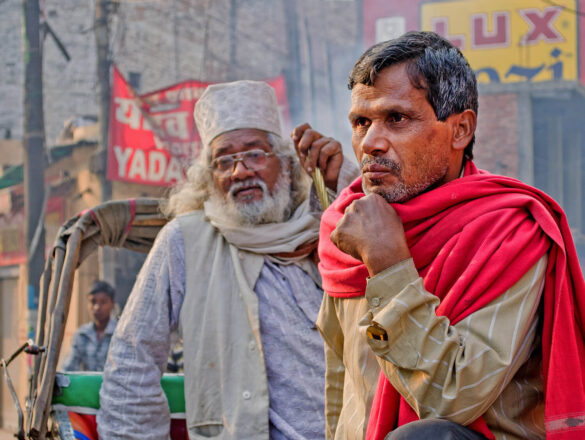 Two men, one in a red shawl and the other with white hair and beard, deep in thought in Varanasi.