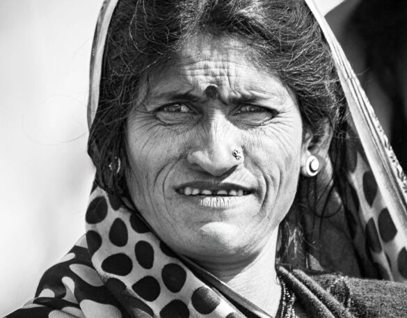 Close-up portrait of an elderly Indian woman with deep lines on her face.