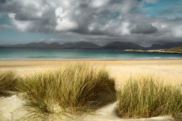 Serene beach scene with golden sands, blue waters, and dramatic clouds at Luskentyre.