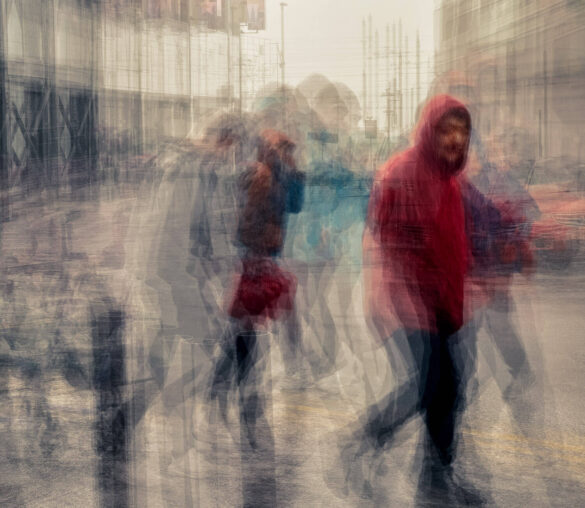 Blurred image of people walking in the city, creating a ghostly effect.