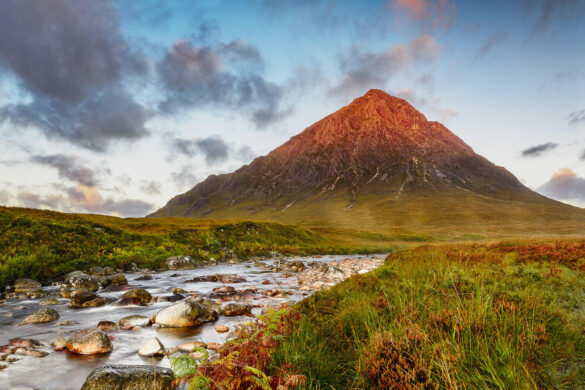 Majestic mountain illuminated by the morning sun, with a flowing stream in the foreground.