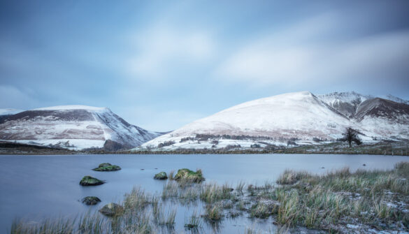 Snow-covered hills reflecting in the calm waters of Tewet Tarn.